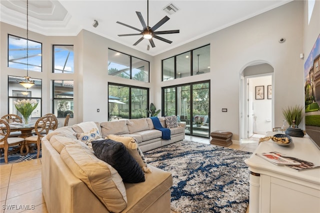 tiled living room with crown molding, ceiling fan, and a high ceiling