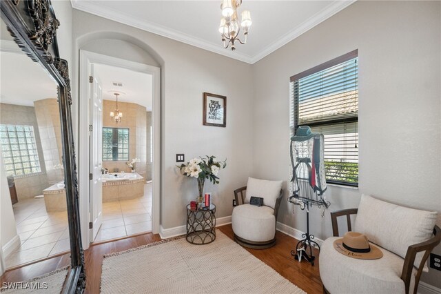 sitting room with hardwood / wood-style floors, ornamental molding, and an inviting chandelier