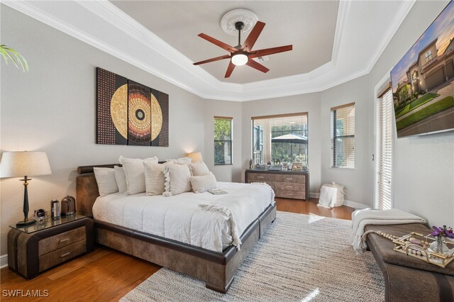 bedroom featuring hardwood / wood-style floors, a tray ceiling, ceiling fan, and crown molding