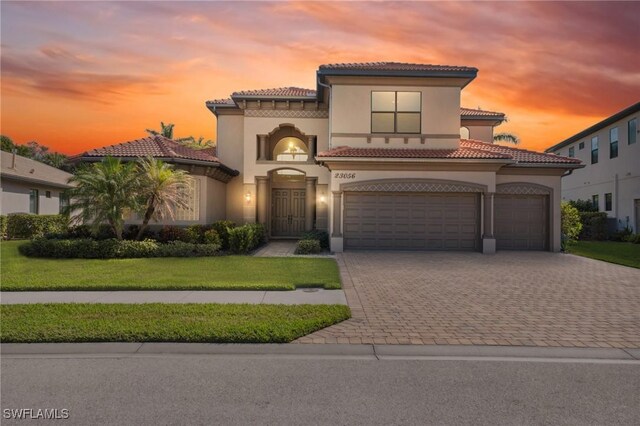 mediterranean / spanish house featuring a lawn and a garage