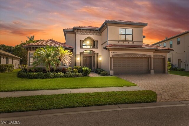 mediterranean / spanish-style house featuring a garage and a yard