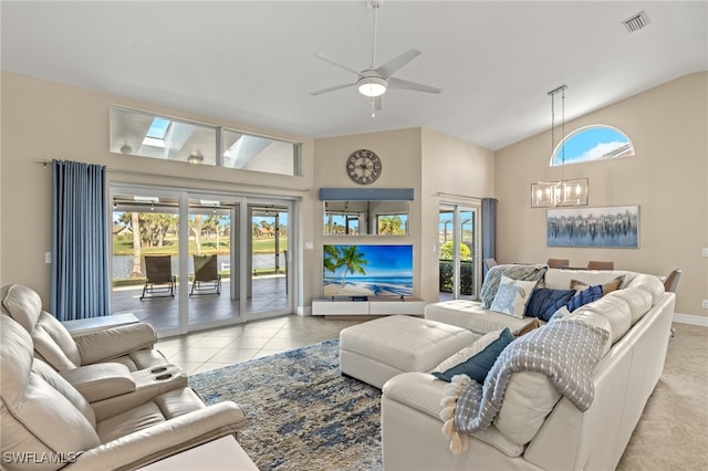 tiled living room featuring visible vents, plenty of natural light, baseboards, and ceiling fan with notable chandelier