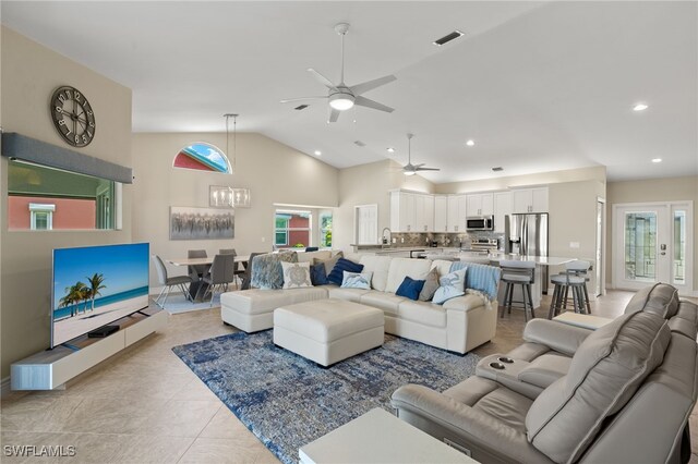 tiled living room with ceiling fan, sink, and high vaulted ceiling