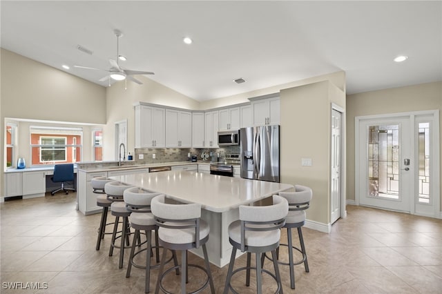 kitchen featuring a breakfast bar area, stainless steel appliances, a sink, visible vents, and light countertops