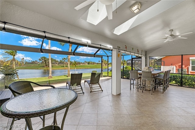 sunroom featuring a ceiling fan, lofted ceiling, and a water view