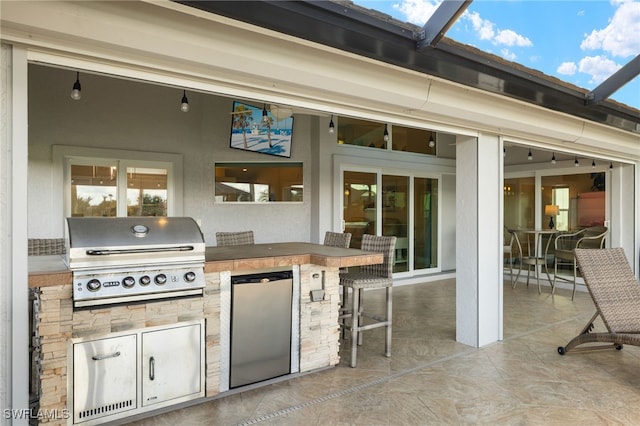 view of patio / terrace featuring grilling area, an outdoor kitchen, a lanai, and outdoor wet bar