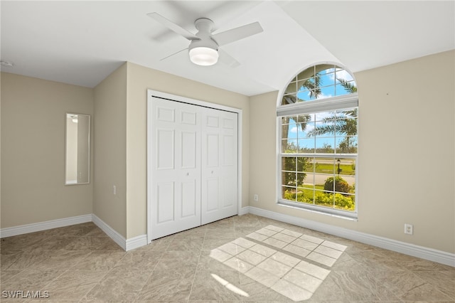 unfurnished bedroom with ceiling fan, baseboards, and a closet