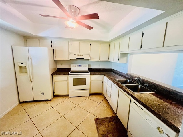 kitchen with sink, light tile patterned floors, exhaust hood, a tray ceiling, and white appliances