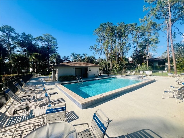 community pool with a patio area and fence