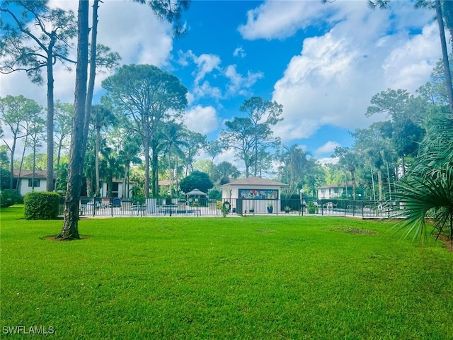 view of community featuring a yard and fence