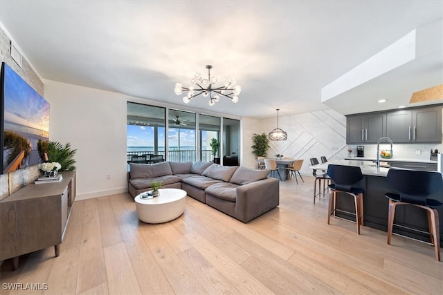 living room with a chandelier, sink, and light hardwood / wood-style floors