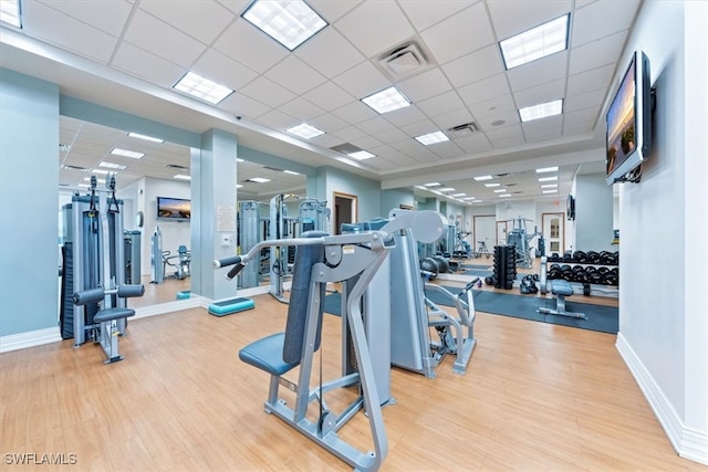 gym with a drop ceiling and light hardwood / wood-style floors