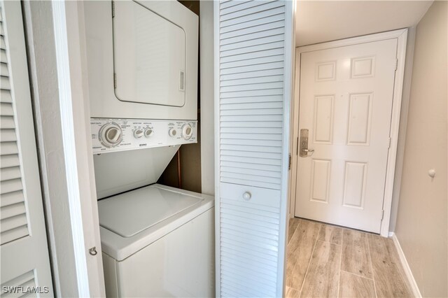 clothes washing area with stacked washer / dryer and light wood-type flooring