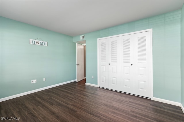 unfurnished bedroom with dark hardwood / wood-style flooring and a closet