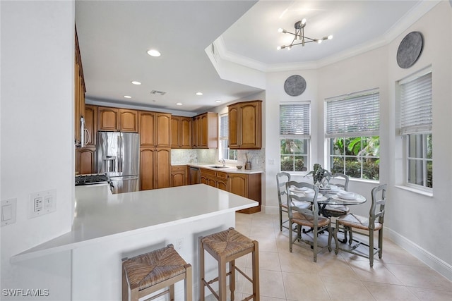 kitchen featuring kitchen peninsula, an inviting chandelier, a breakfast bar area, appliances with stainless steel finishes, and sink