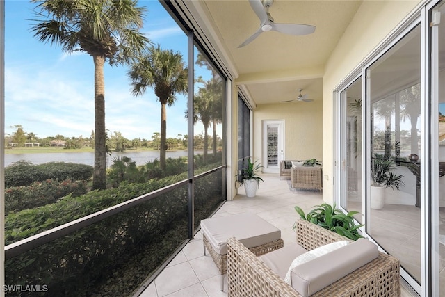 sunroom featuring ceiling fan and a water view