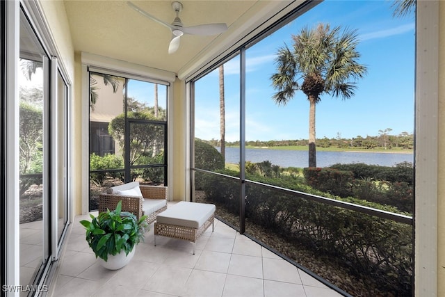 sunroom featuring ceiling fan and a water view