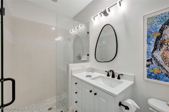 bathroom with toilet, vanity, and a shower with shower door