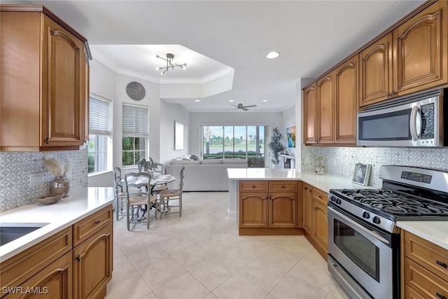 kitchen featuring kitchen peninsula, backsplash, crown molding, and appliances with stainless steel finishes