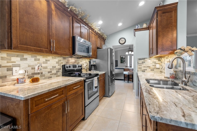 kitchen with backsplash, lofted ceiling, sink, and appliances with stainless steel finishes