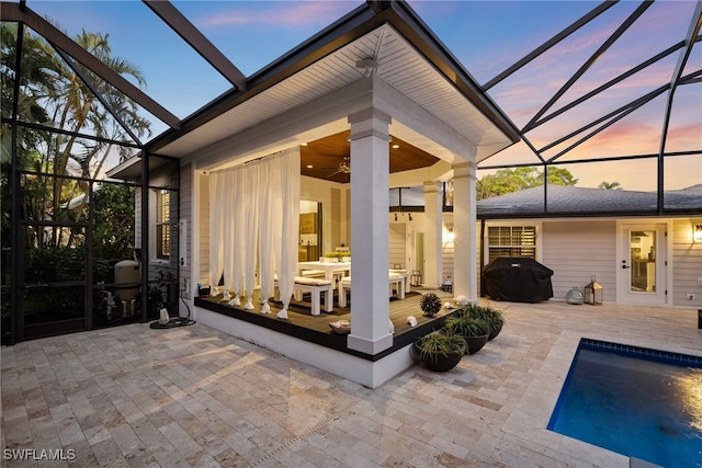 patio terrace at dusk featuring a lanai, a grill, and ceiling fan