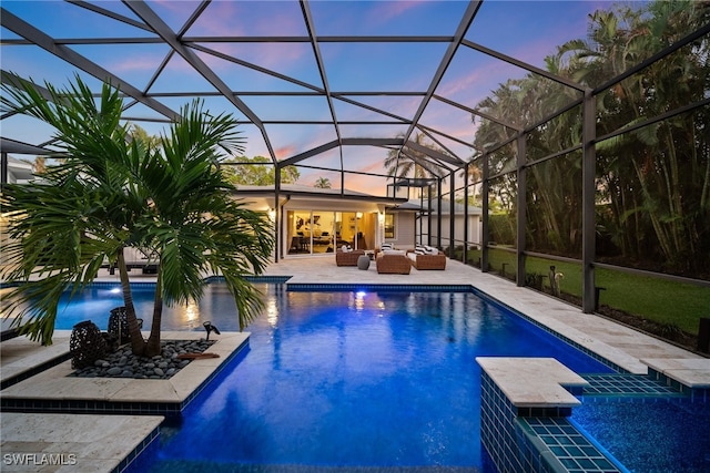 pool at dusk featuring outdoor lounge area, a patio area, and a lanai