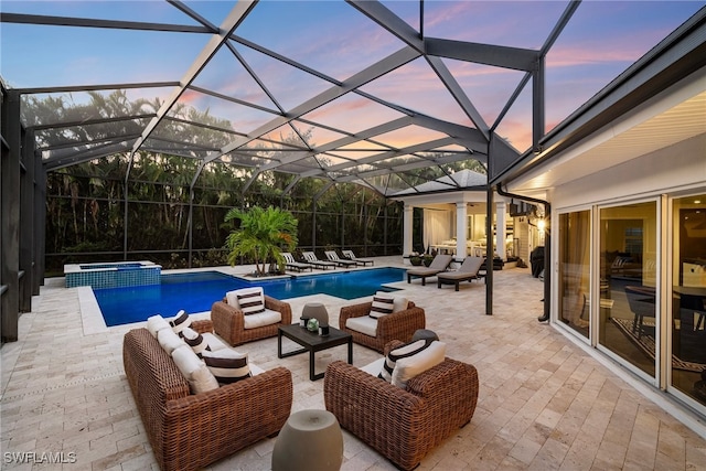 pool at dusk featuring an in ground hot tub, an outdoor living space, a patio area, and a lanai