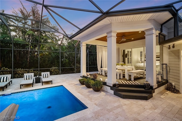 pool at dusk with ceiling fan, an outdoor living space, a patio, and glass enclosure