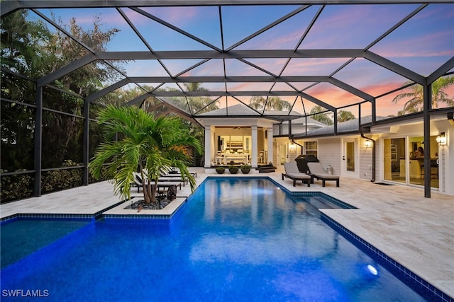 pool at dusk with ceiling fan, a patio area, and a lanai