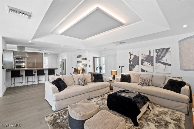 living room with hardwood / wood-style floors and a tray ceiling