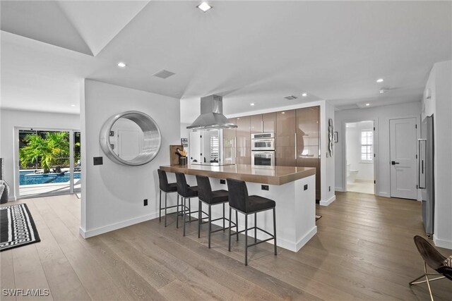 kitchen featuring kitchen peninsula, appliances with stainless steel finishes, a wealth of natural light, extractor fan, and a breakfast bar area