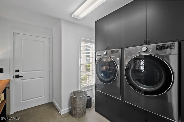 laundry area with separate washer and dryer and cabinets