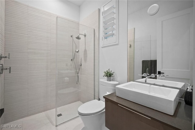 bathroom featuring tile patterned flooring, vanity, toilet, and a shower with door