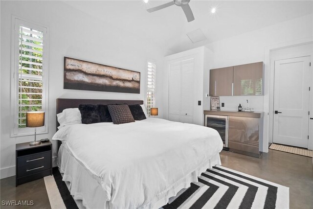 bedroom featuring wine cooler, ceiling fan, and a closet