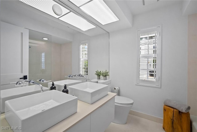 bathroom featuring tile patterned flooring, vanity, a skylight, and toilet