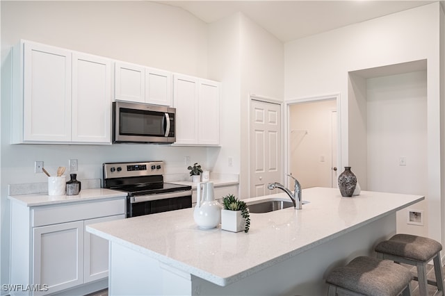 kitchen featuring a breakfast bar, sink, an island with sink, appliances with stainless steel finishes, and white cabinetry