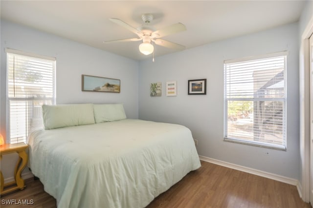 bedroom featuring dark hardwood / wood-style flooring, multiple windows, and ceiling fan