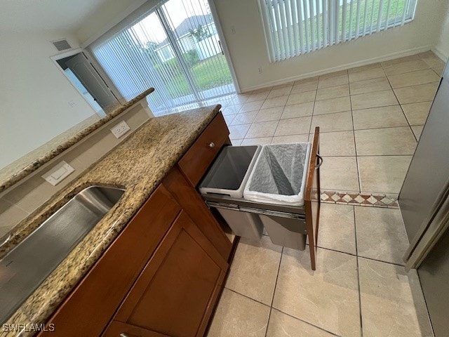 kitchen featuring light tile patterned flooring, sink, and stone countertops