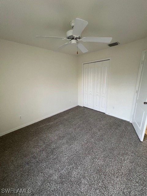 unfurnished bedroom featuring ceiling fan, dark colored carpet, and a closet