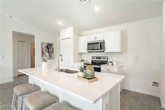 kitchen with white cabinets, a center island with sink, sink, appliances with stainless steel finishes, and dark hardwood / wood-style flooring