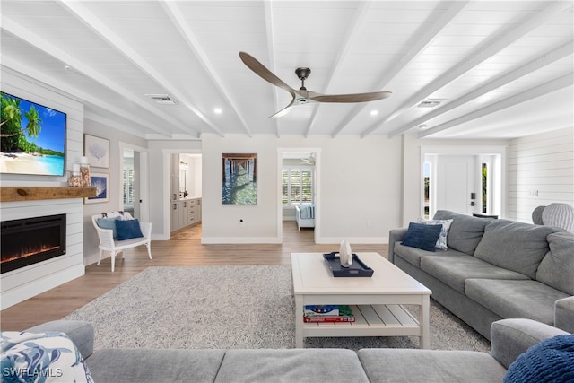 living room featuring beam ceiling, light hardwood / wood-style floors, and ceiling fan