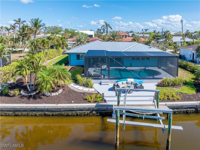 rear view of property with a lanai, a patio area, a water view, and a pool