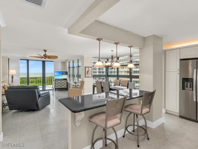 260 Seaview Ct Unit 803, Marco Island, FL 34145 - kitchen featuring dark stone counters, a breakfast bar, visible vents, light tile patterned flooring, and stainless steel refrigerator with ice dispenser
