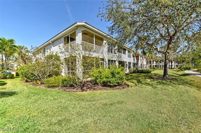 view of side of property with a balcony and a lawn