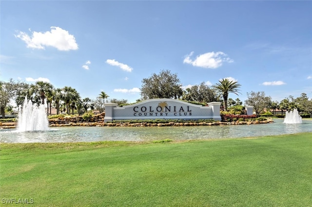 community / neighborhood sign with a water view and a lawn