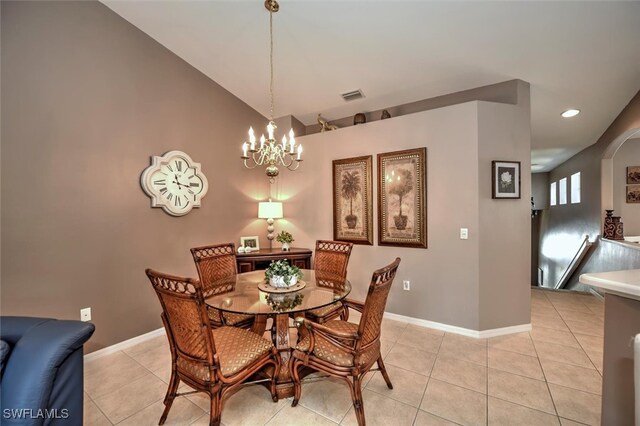 tiled dining space featuring an inviting chandelier and vaulted ceiling