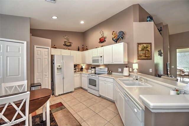 kitchen featuring sink, kitchen peninsula, white appliances, white cabinets, and vaulted ceiling