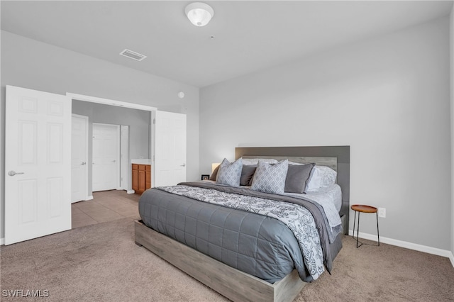 bedroom featuring ensuite bath and carpet