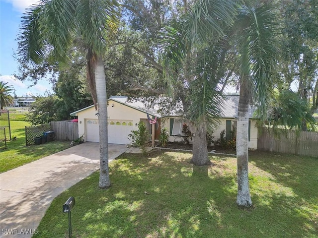 view of front facade with a front yard, fence, driveway, stucco siding, and a garage