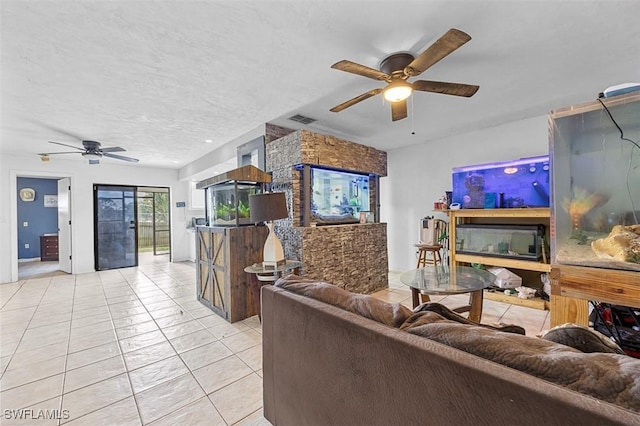 living area with light tile patterned floors, visible vents, a textured ceiling, and a ceiling fan